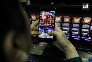 Seorang pemain menggunakan smartphone untuk bermain permainan slot online dengan tampilan grafis yang menarik.